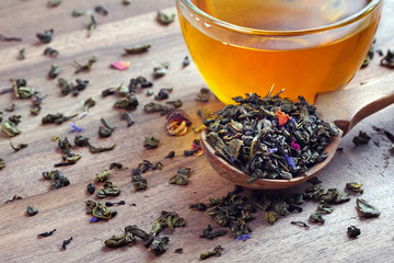 blended tea. green tea with dry flower petals. dry leaves of green tea in a wooden spoon and glass...
