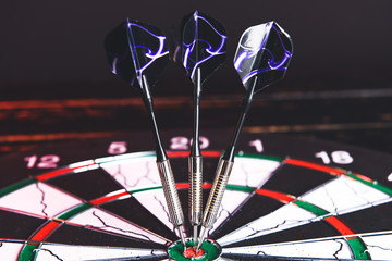 Dartboard with hit bullseye on dark background, closeup