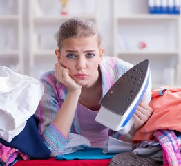 Sad woman ironing clothing at home