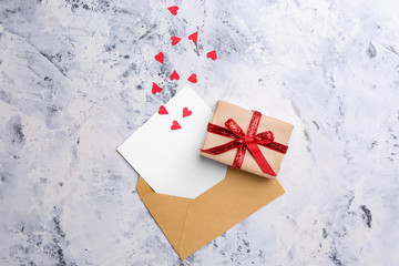 Gift for Valentine's Day, envelope and red hearts on light background