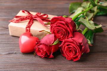 Gift for Valentine's Day, rose flowers and red heart on wooden background