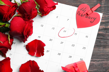 Calendar and rose flowers on wooden background. Valentine's Day celebration
