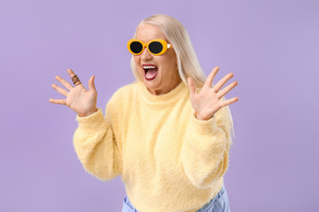 Crazy fashionable mature woman on color background