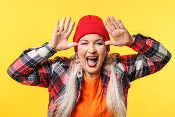 Crazy fashionable mature woman on color background