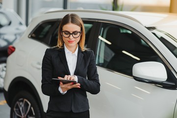 Beautiful young woman buys a car in the dealership saloon.