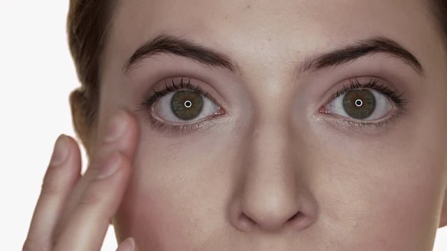 Close up shot of woman making up face with creme to hide eye rings