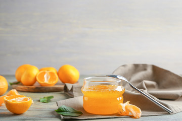 Composition with jar of sweet jam and tangerines on table