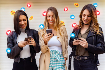 Three young adult woman social media influencers smiling, using apps and sending emoticons 