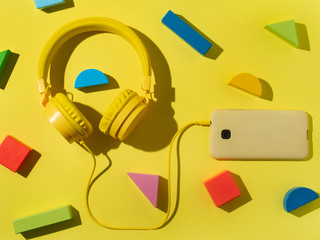 a pair of headphones connected to a smartphone surrounded by colorful blocks
