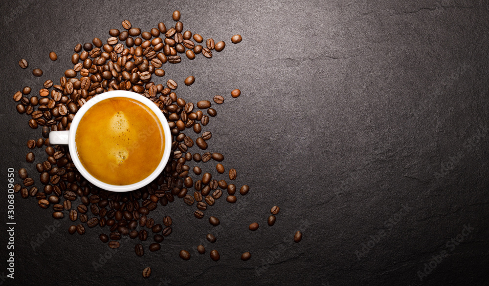 Wall mural Cup of coffee and coffee beans on black background