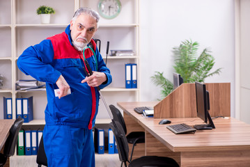 Old professional contractor doing pest control in the office