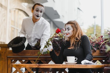 mime guy and girl in cafe drinking coffee. Mime in front of Paris cafe acting like drinking tea or coffee.