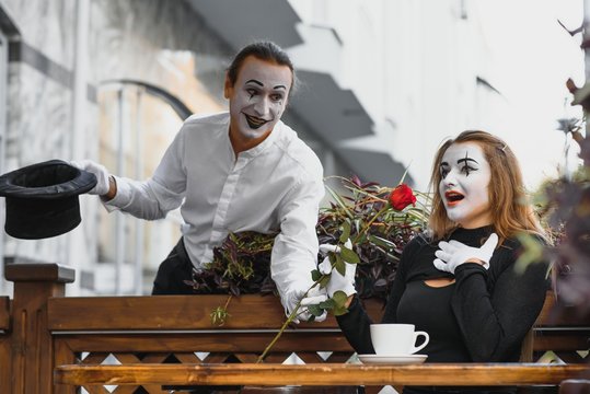 mime guy and girl in cafe drinking coffee. Mime in front of Paris cafe acting like drinking tea or coffee.