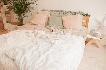 cozy large bright bed, with a rumpled fluffy white plaid, pink and green pillows