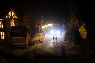 Fototapeta na wymiar New Year miniature house in the snow at night with fir tree. Holiday concept. Selective focus