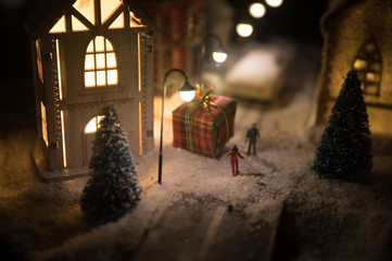 Fototapeta na wymiar New Year miniature house in the snow at night with fir tree. Holiday concept. Selective focus