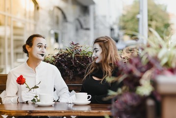 mime guy and girl in cafe drinking coffee. Mime in front of Paris cafe acting like drinking tea or coffee.