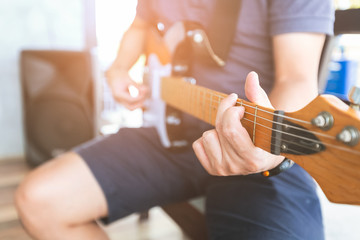 Close-up Man hands playing acoustic guitar with light flare.