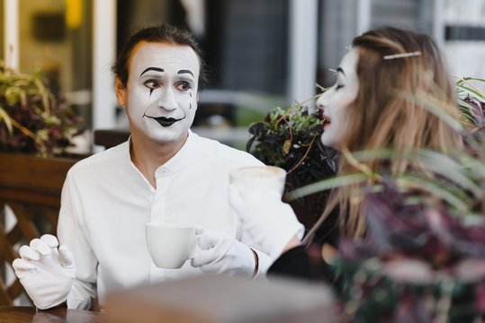 Mimes in front of Paris cafe acting like drinking tea or coffee.