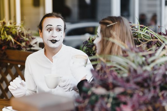Mimes in front of Paris cafe acting like drinking tea or coffee.