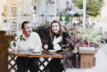 mime guy and girl in cafe drinking coffee. Mime in front of Paris cafe acting like drinking tea or coffee.
