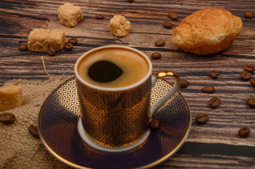 Coffee Cup, croissants, brown sugar and coffee beans on wooden background. Close up.