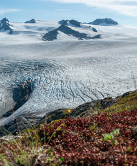 A distant tent appears small next to a huge glacier