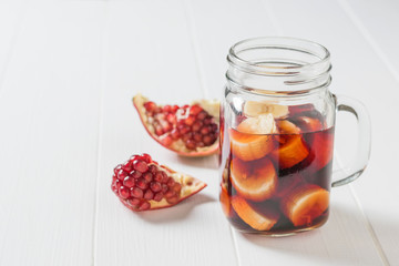 Banana slices in pomegranate juice and fresh pomegranate seeds on a white table.