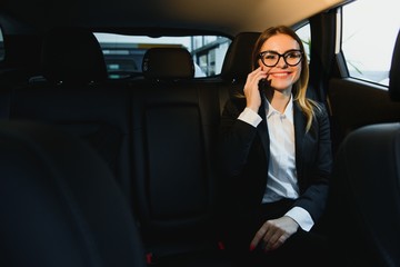 Beautiful successful businesswoman talk on her mobile phone in a backseat of a car