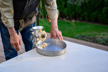 Senior man using manual grinder to grind up fresh razor clams for chowder, catch pan, and table