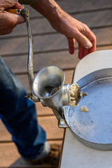 Senior man using manual grinder to grind up fresh razor clams for chowder, catch pan, and table
