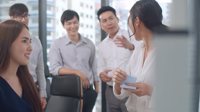 Asia businessmen and businesswomen meeting brainstorming ideas conducting business presentation project colleagues working together plan success strategy enjoy teamwork in small modern office.