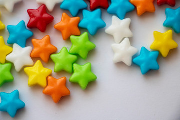 Obraz premium Isolated Candy Stars Close Up Colorful candy stars used for decorating cookies, treats and gingerbread houses. Macro view. White background. Fun and sweet. 
