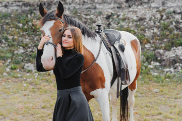 Portrait of young pretty cheerful woman with horse at summer