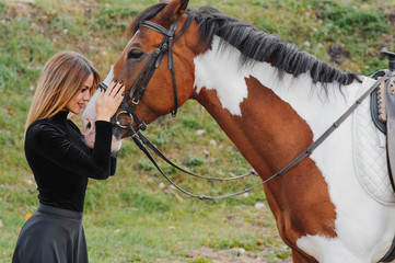 Portrait of young pretty cheerful woman with horse at summer