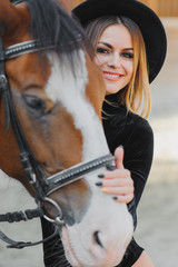 Portrait of young pretty cheerful woman with horse at summer