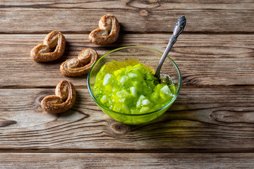 Cucumber jam in a plate with cookies on a wooden background