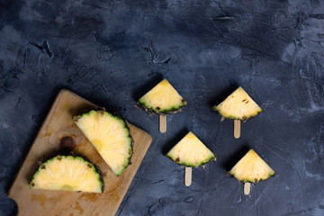 Slices of fresh Pineapple on simple grey background, from above. Top view. Copy space for designer.