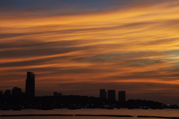 Colorful twilight cloud over a city silhouette and sea in an evening
