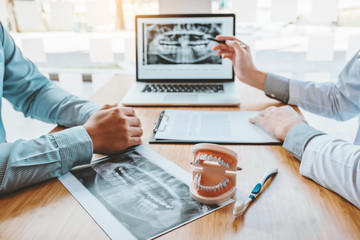 Dentist with male patient presenting discussing dental problems x-ray image film in dental office