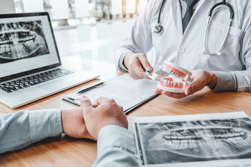 Dentist with male patient presenting discussing dental problems x-ray image film in dental office