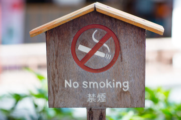No smoking sign against a wood wall. The white non-smoking sign on the wooden floor is a sign that the traveler is aware of being a non-smoker. .Non Smoking sign on pole