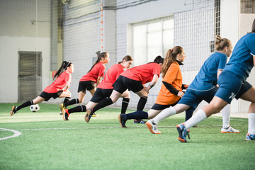 Group of active female footballers in sportswear doing exercise for stretching