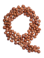 Letter Q of the English alphabet from from hazelnut on a white isolated background. Food pattern made from nuts. Bright alphabet for shops.