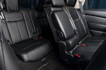Clean after washing the rear passenger seats of matte black genuine leather inside the interior with three rows and seven seater of an expensive SUV, preparation before selling the car.