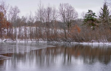 Reflections on a lake along the snowy woods