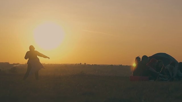 silhouette of positive overweight woman dances in camp on wide meadow in autumn evening at back sunset light slow motion