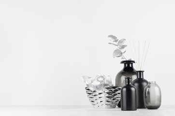 Aromatherapy black bottles with sticks and silver bowl, leaves on soft light white table with copy...