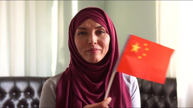 Portrait of  happy muslim woman in hijab with flag of China. Immigration and religion concept