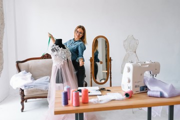 happy young fashion deisgner in her studio. concept of tailoring